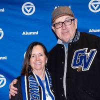 Two people standing in front GVSU backdrop and smiling at camera